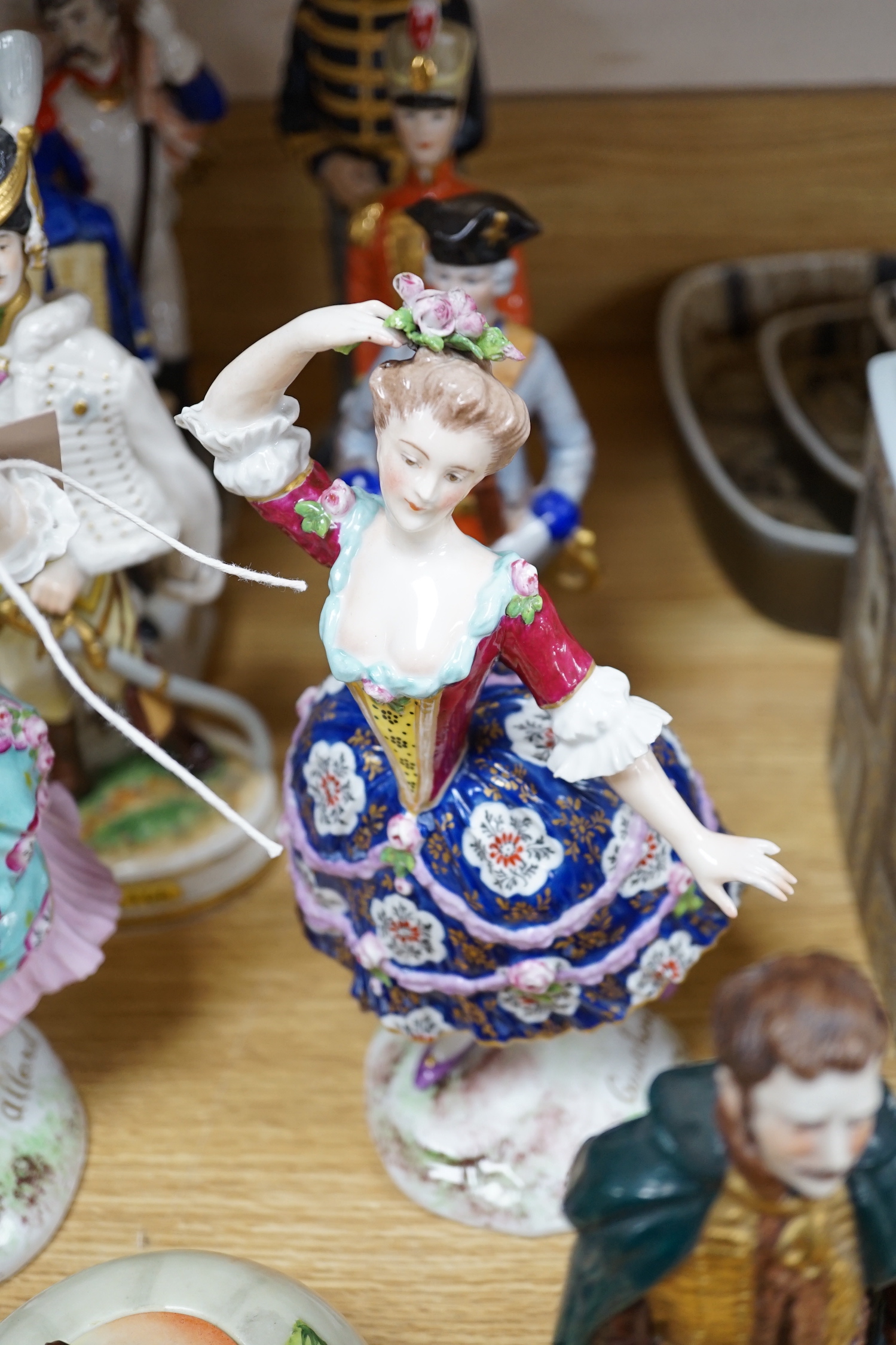 A group of Continental porcelain military figures, two porcelain figures of dancing females and four pieces of tableware in the form of fruit